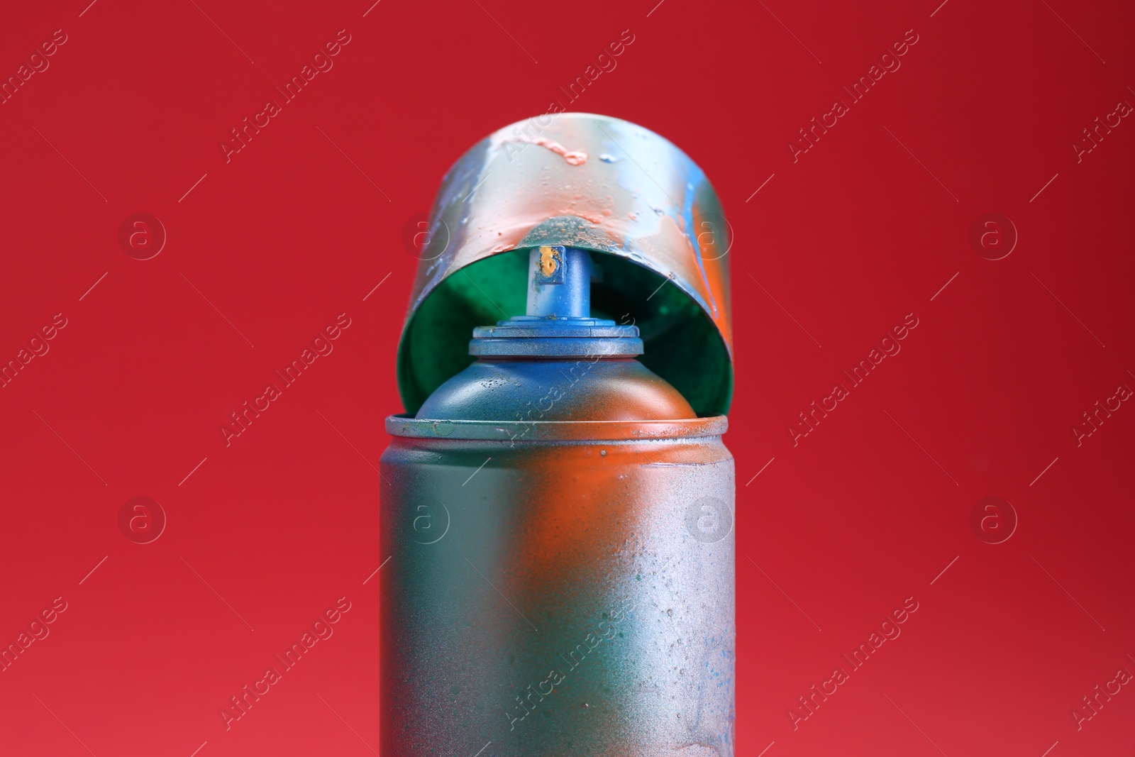 Photo of One can of bright spray paint with cap on red background, closeup