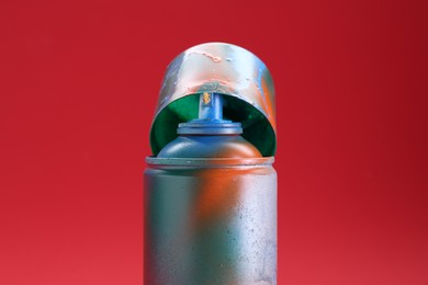 One can of bright spray paint with cap on red background, closeup