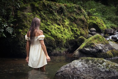 Photo of Beautiful young woman in mountain river outdoors, back view. Space for text