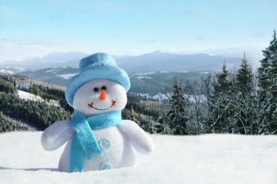 Image of Cute small decorative snowman outdoors on sunny day, space for text