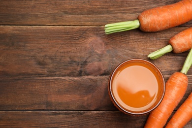 Photo of Flat lay composition with carrots and juice on wooden table, space for text