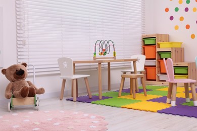 Stylish kindergarten interior with table, shelving unit and different toys