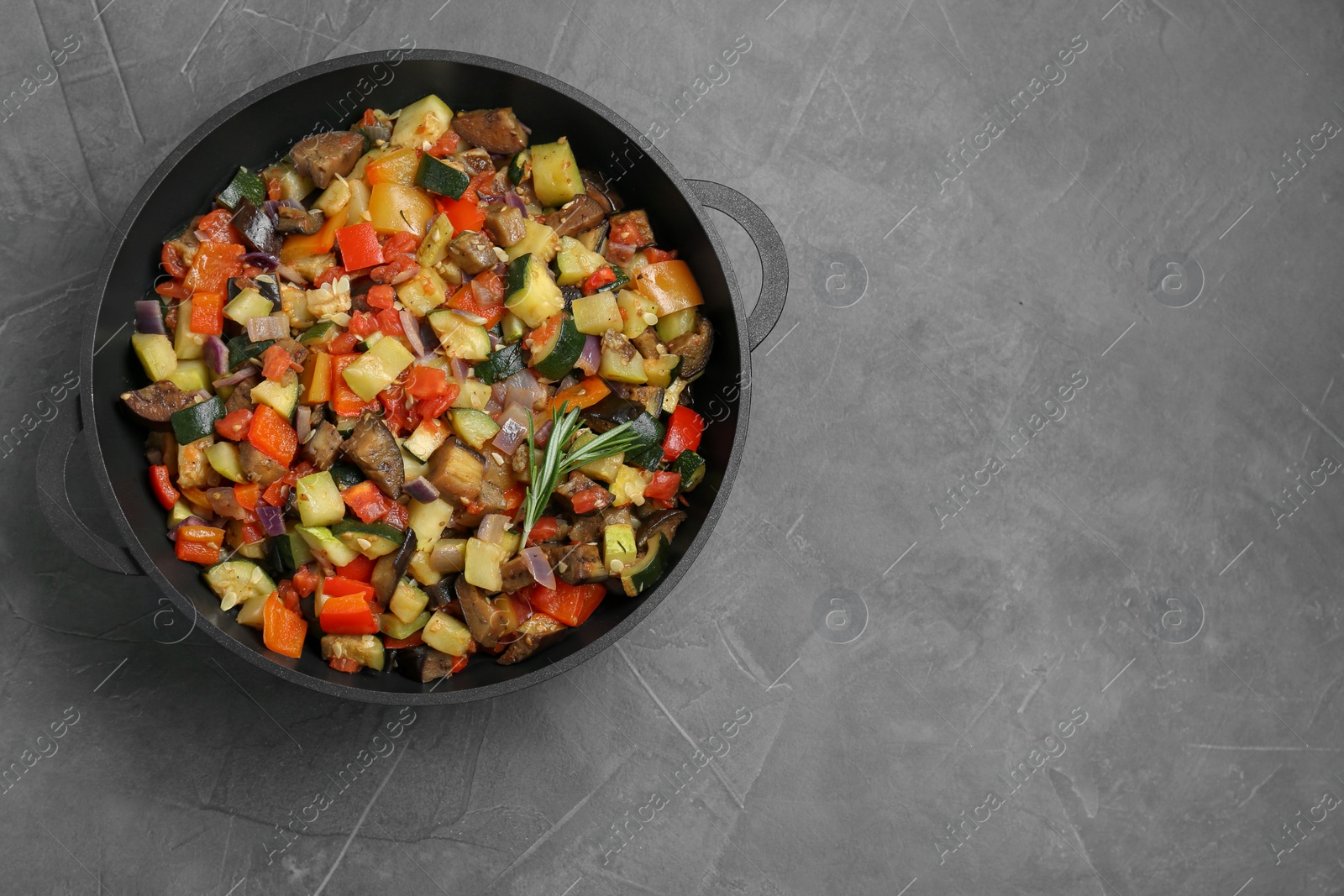 Photo of Delicious ratatouille in baking dish on grey table, top view. Space for text