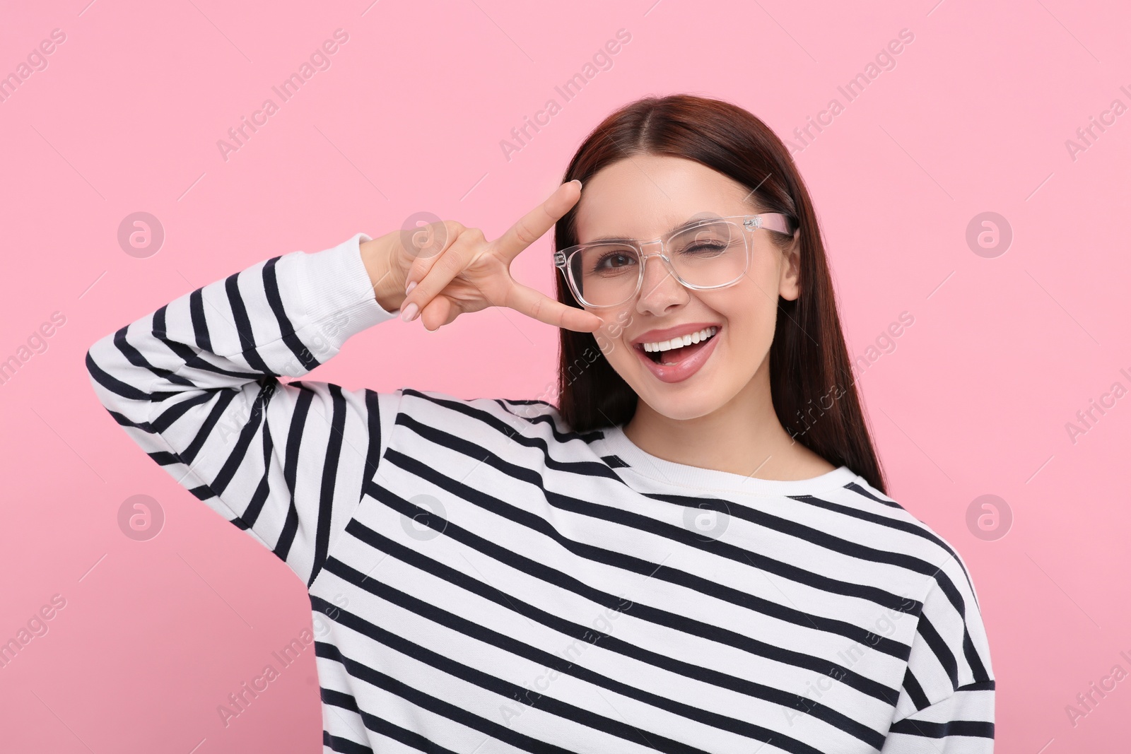 Photo of Portrait of woman in stylish eyeglasses gesturing on pink background