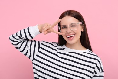 Portrait of woman in stylish eyeglasses gesturing on pink background