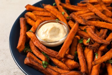 Photo of Delicious sweet potato fries served with sauce on light table, closeup