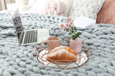 Photo of Tray with tasty breakfast, laptop and book on bed