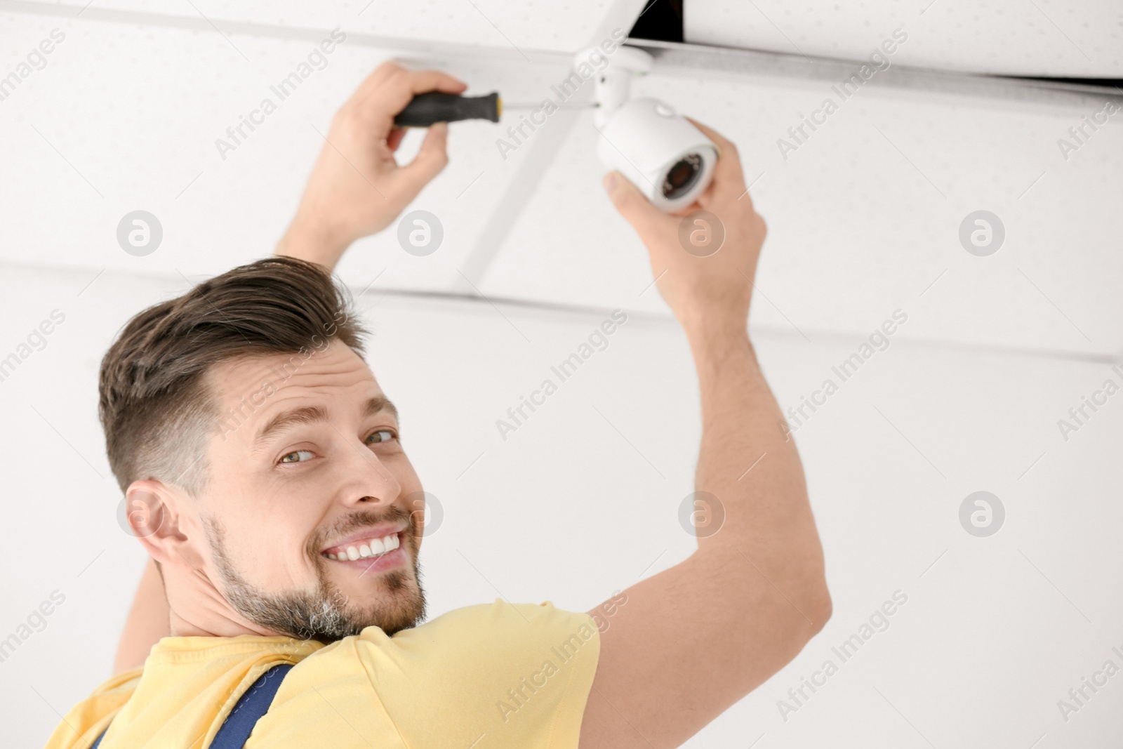 Photo of Technician installing CCTV camera on ceiling indoors