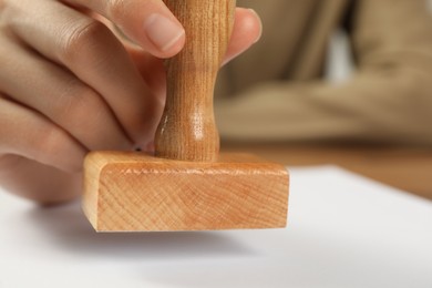 Woman stamping blank sheet of paper at table, closeup