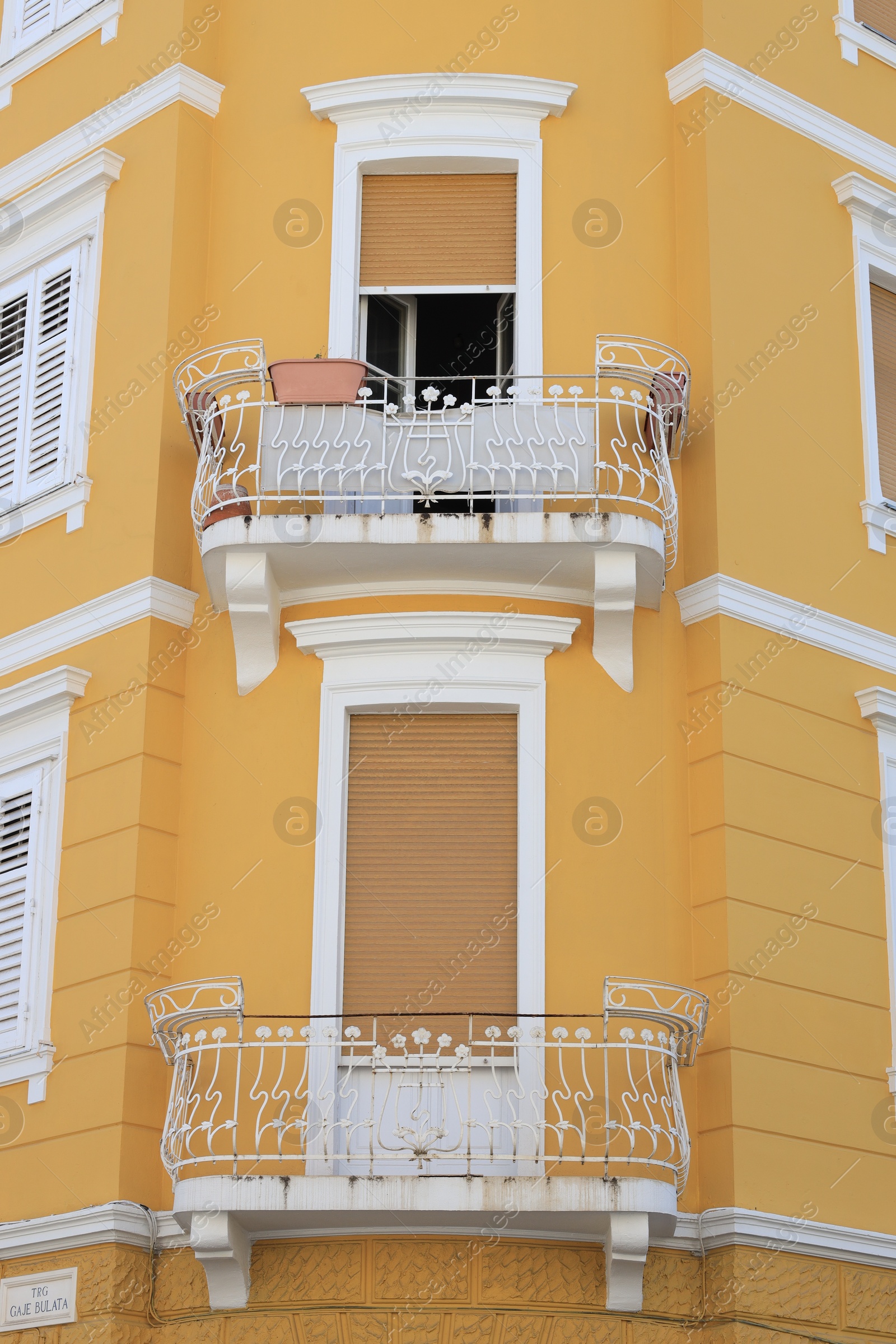 Photo of View of beautiful yellow building with balconies outdoors