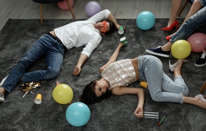 Photo of Group of friends sleeping in messy room after party, view from above