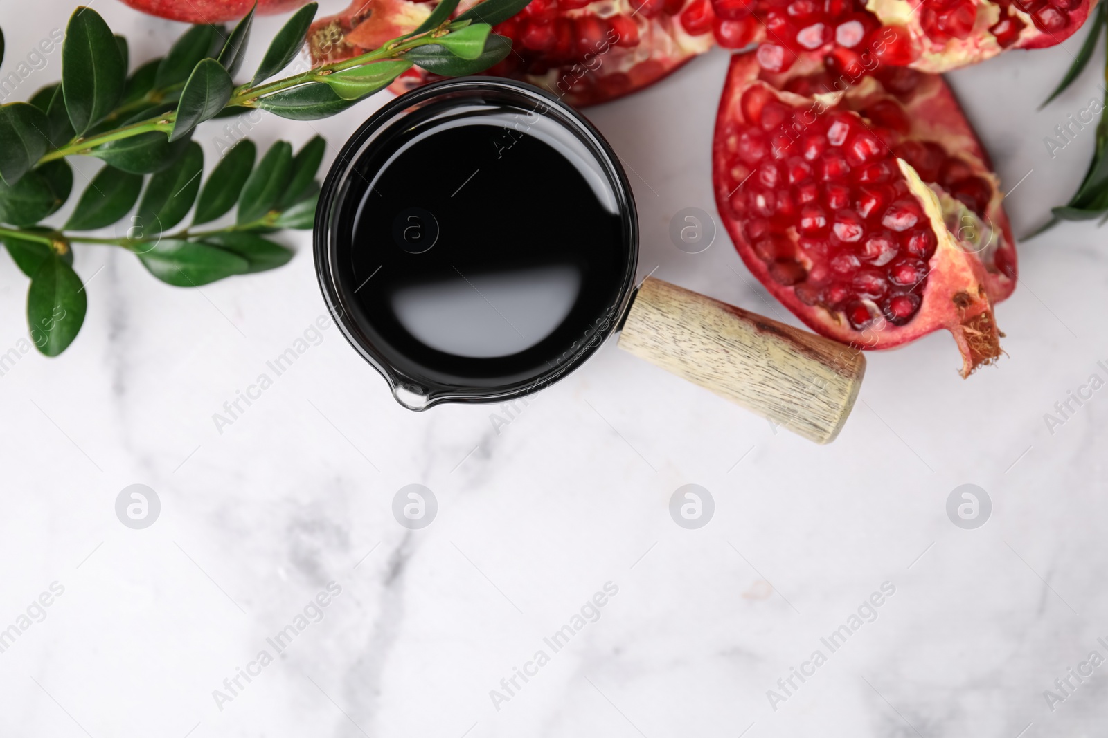 Photo of Tasty pomegranate sauce, fruits and branches on white marble table, flat lay. Space for text