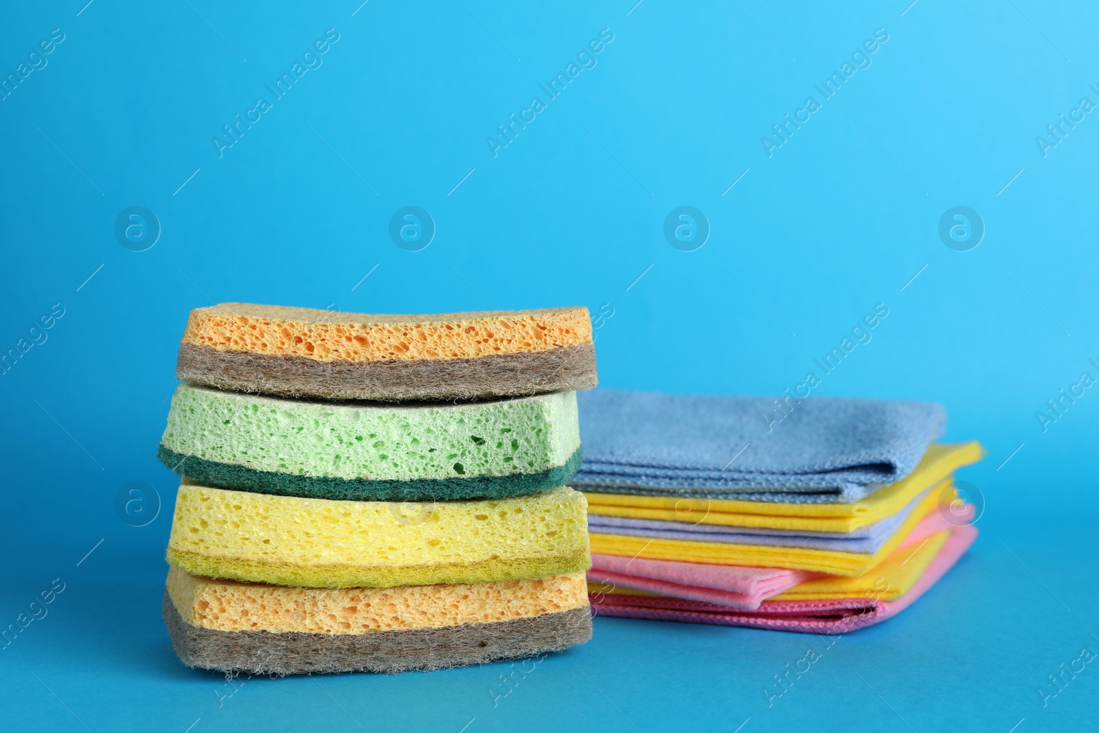 Photo of Color sponges and rags on light blue background
