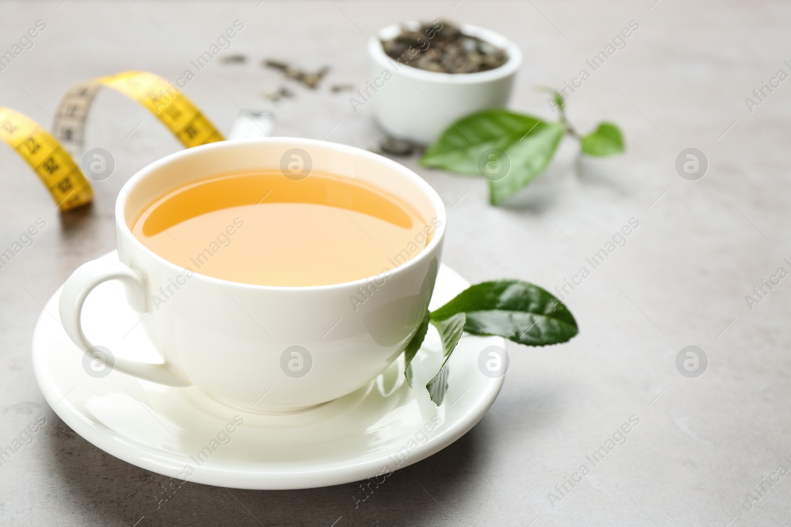 Photo of Cup of herbal diet tea and measuring tape on light table