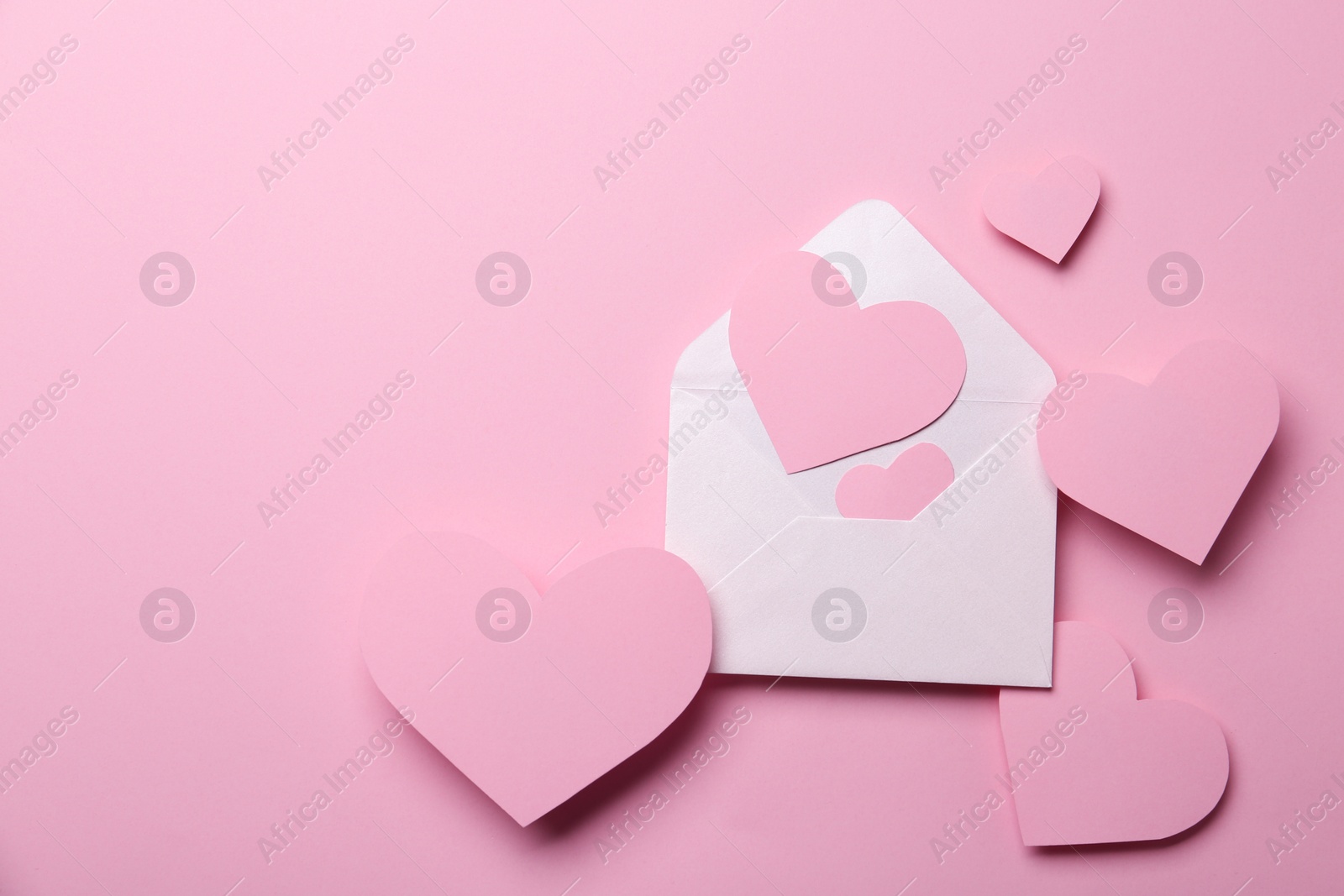 Photo of Paper hearts and envelope on pink background, flat lay