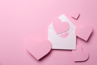 Paper hearts and envelope on pink background, flat lay