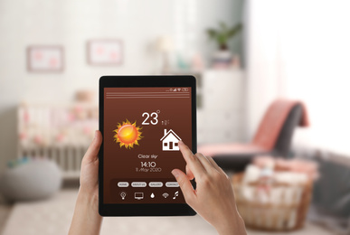 Woman using tablet to set indoor temperature, closeup. Smart home automation system