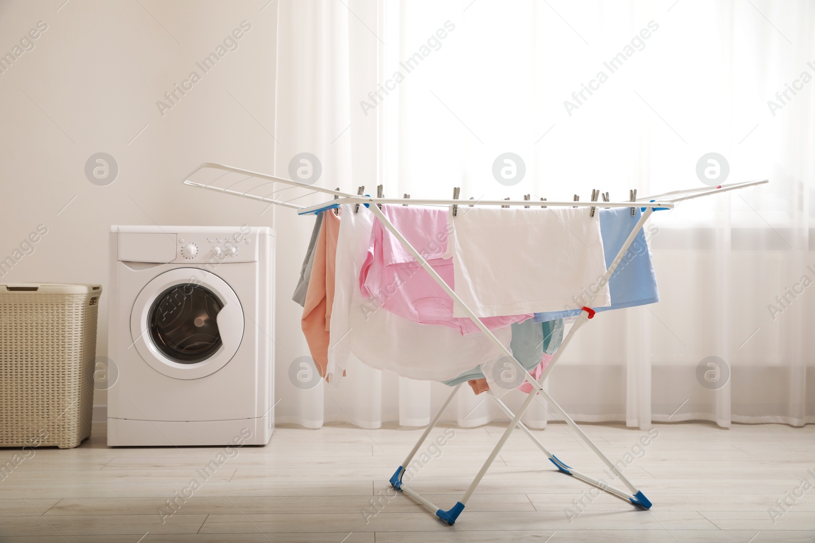 Photo of Clean laundry hanging on drying rack indoors