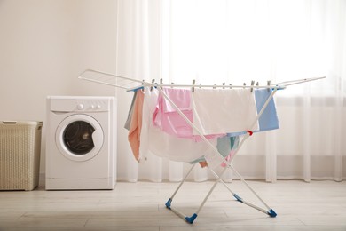 Clean laundry hanging on drying rack indoors