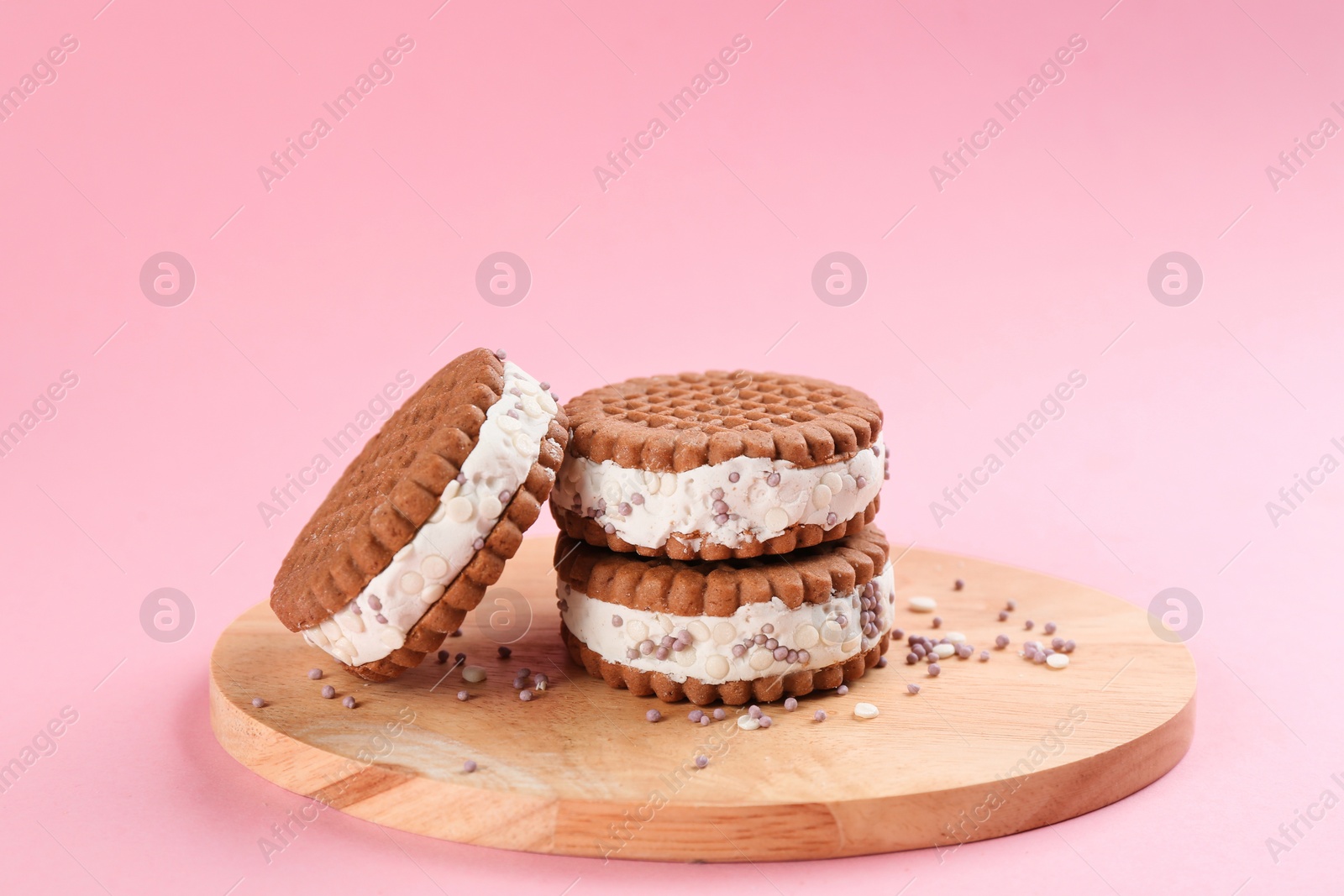 Photo of Sweet delicious ice cream cookie sandwiches on pink background