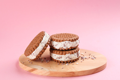 Photo of Sweet delicious ice cream cookie sandwiches on pink background