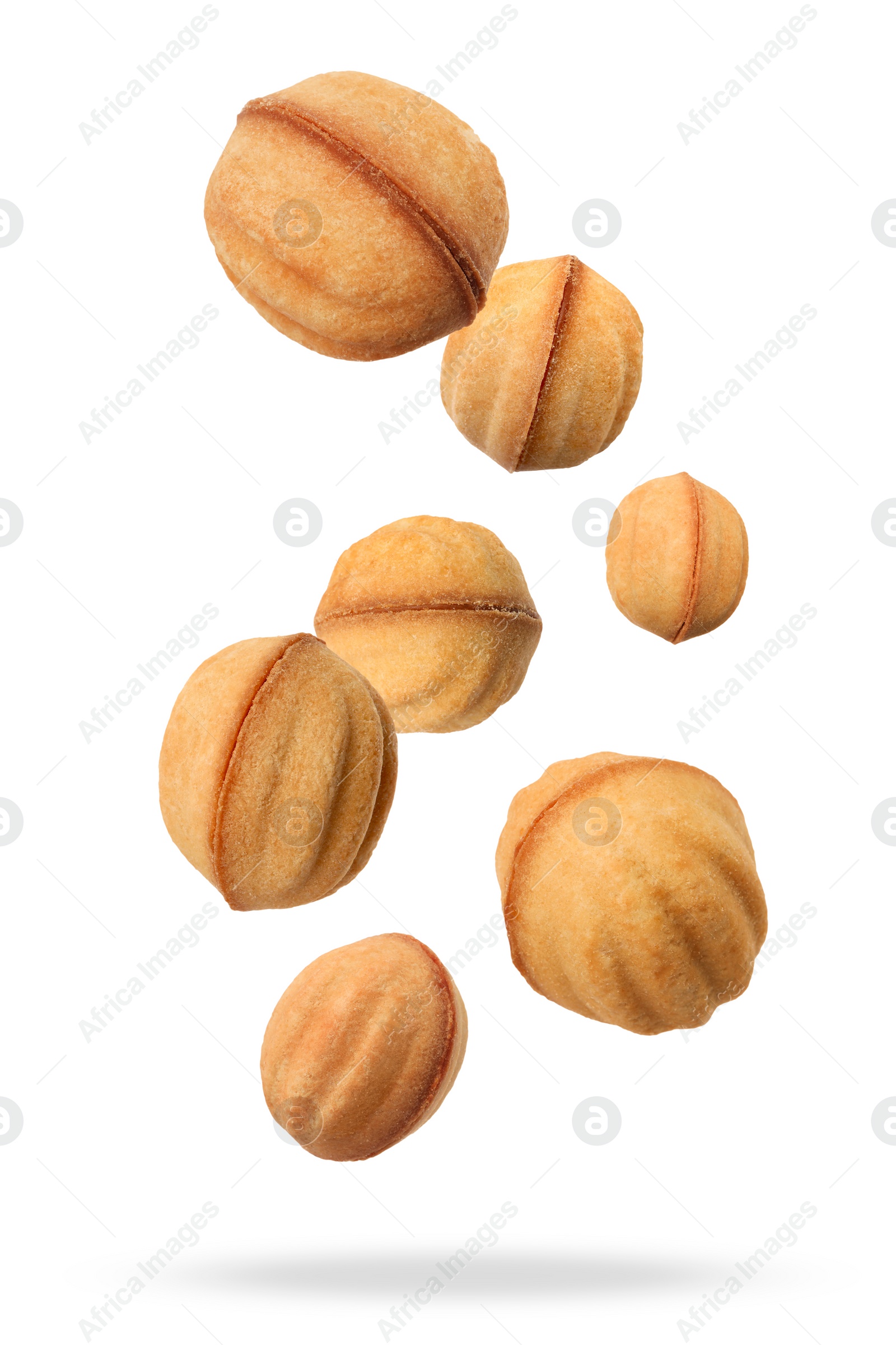 Image of Many delicious nut shaped cookies with caramelized condensed milk falling on white background