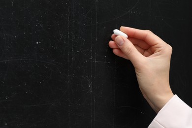 Teacher writing with chalk on black chalkboard, closeup. Space for text