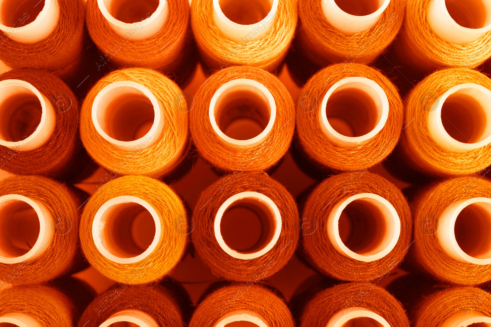 Image of Set of orange sewing threads as background, top view