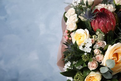 Photo of Beautiful bouquet with roses on light blue background, closeup. Space for text