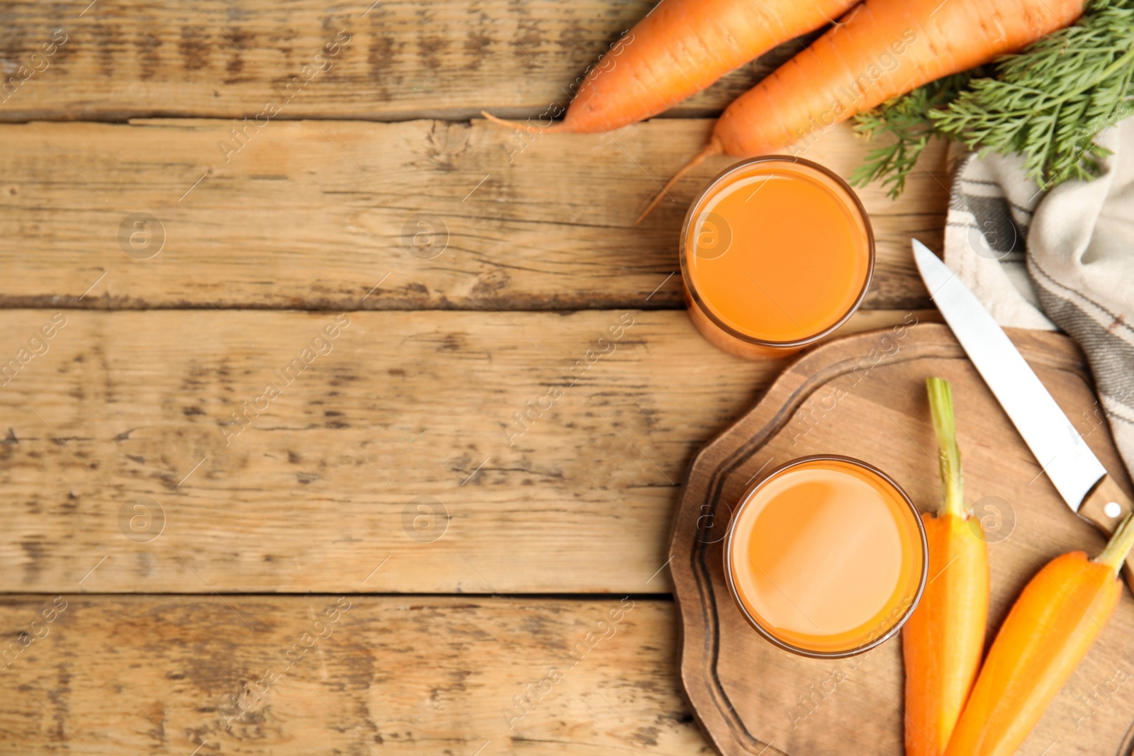 Photo of Freshly made carrot juice on wooden table, flat lay. Space for text