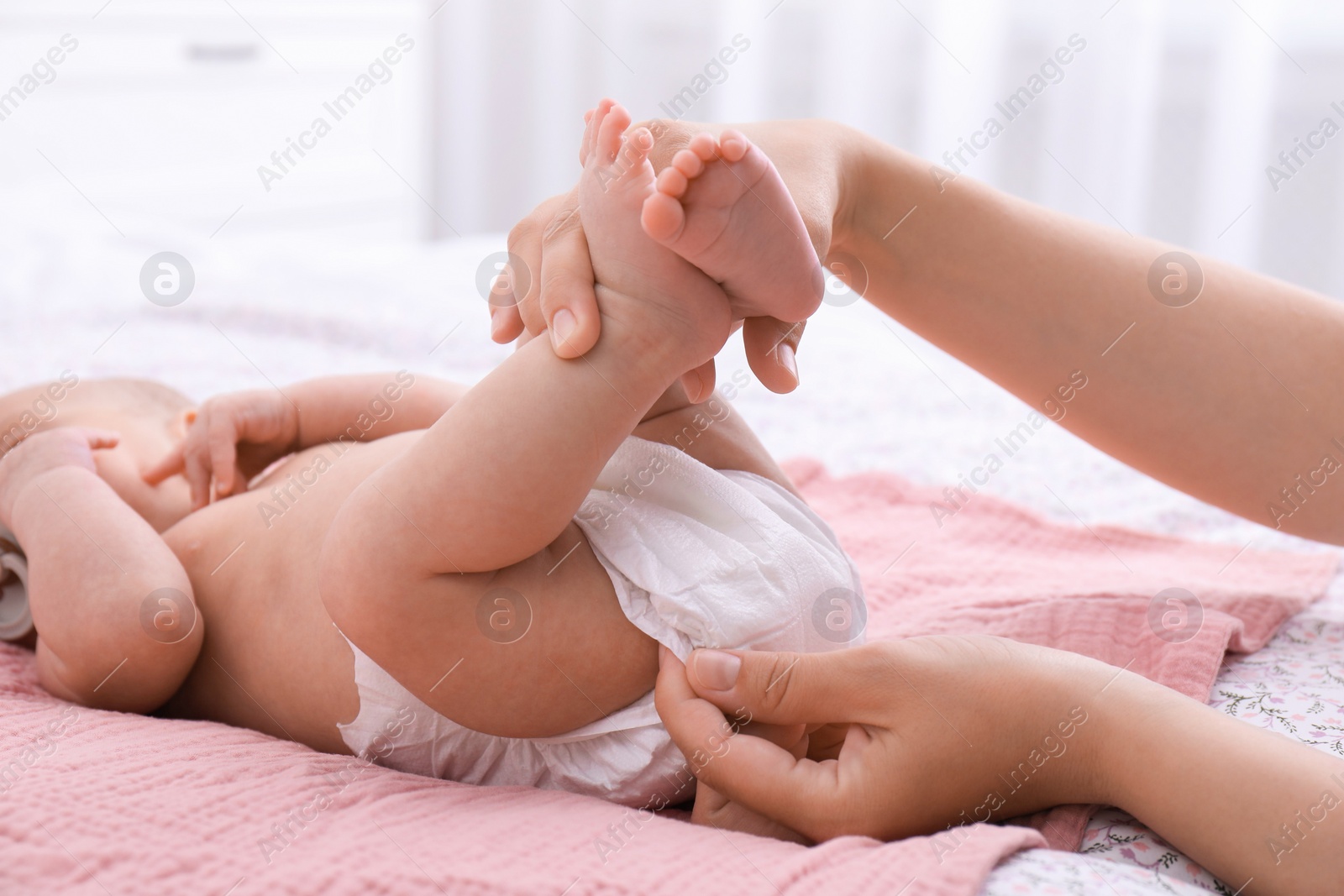 Photo of Mom changing baby's diaper on bed at home, closeup