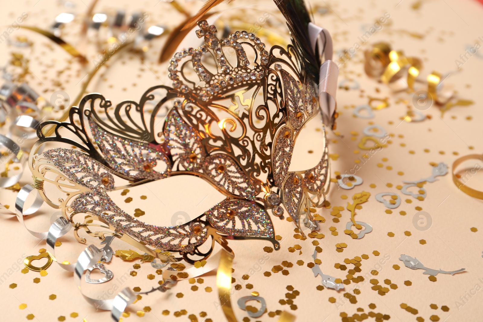 Photo of Beautiful carnival mask and party decor on beige background, closeup