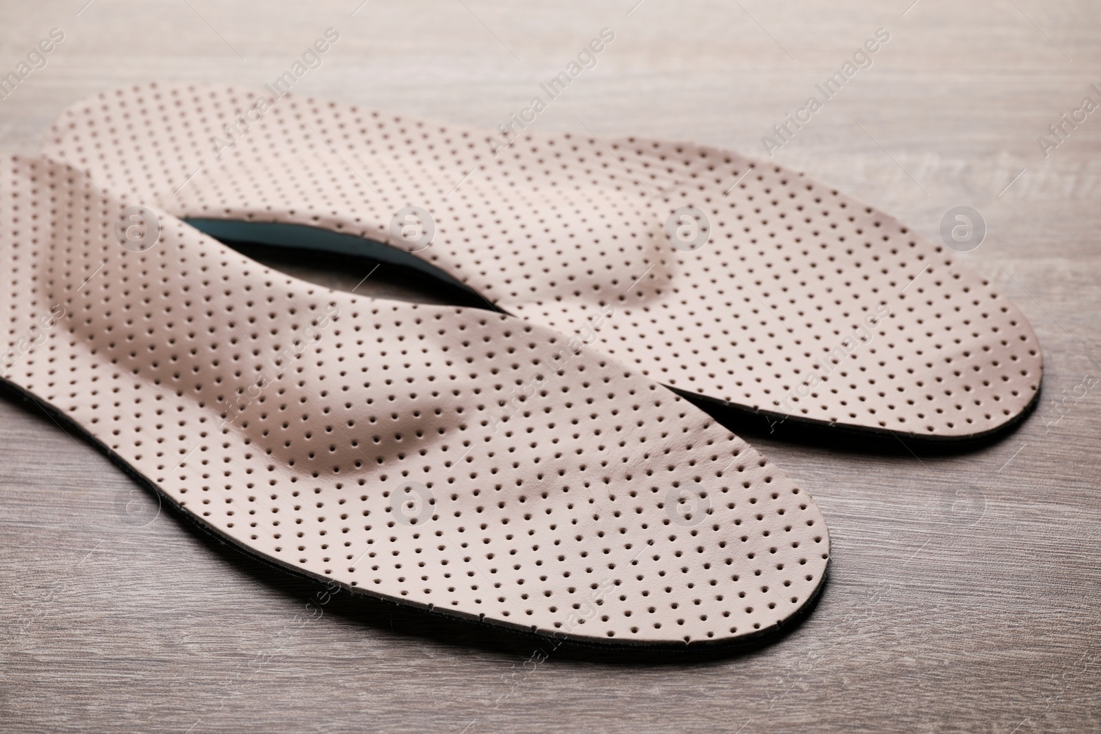 Photo of Beige orthopedic insoles on wooden background, closeup