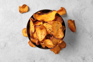 Bowl and sweet potato chips on light table, top view