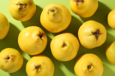 Tasty ripe quinces on light green background, flat lay
