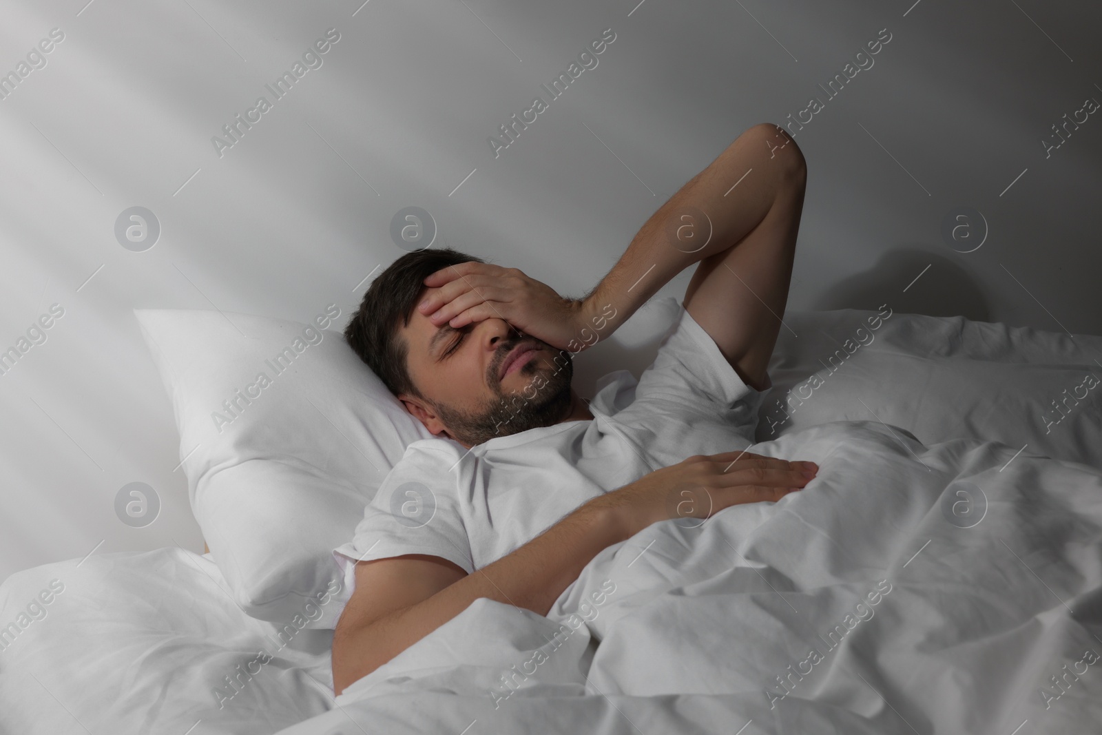 Photo of Sleepy man awaking in bed at home