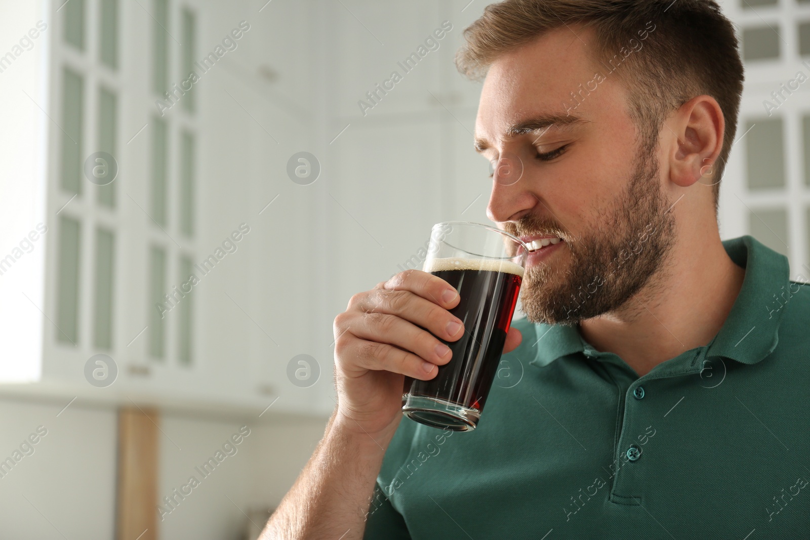 Photo of Handsome man with cold kvass indoors. Traditional Russian summer drink