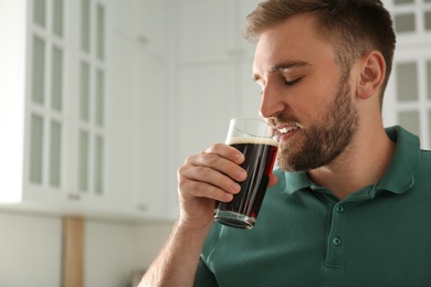 Handsome man with cold kvass indoors. Traditional Russian summer drink