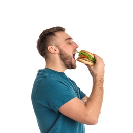 Young man eating tasty burger on white background