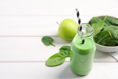 Photo of Tasty fresh green smoothie near ingredients on white wooden table, space for text