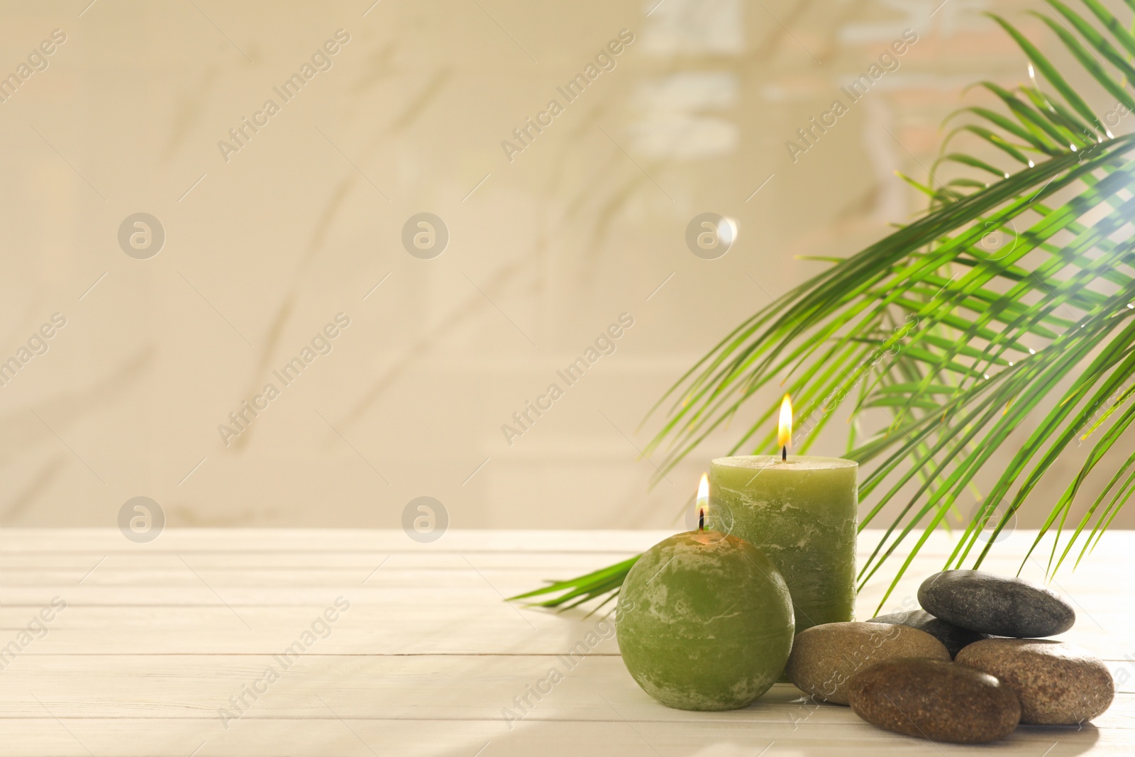 Photo of Composition with spa stones and candles on white wooden table. Space for text