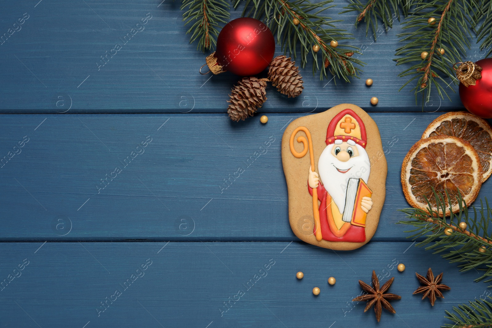 Photo of Tasty gingerbread cookie and festive decor on blue wooden table, flat lay with space for text. St. Nicholas Day celebration