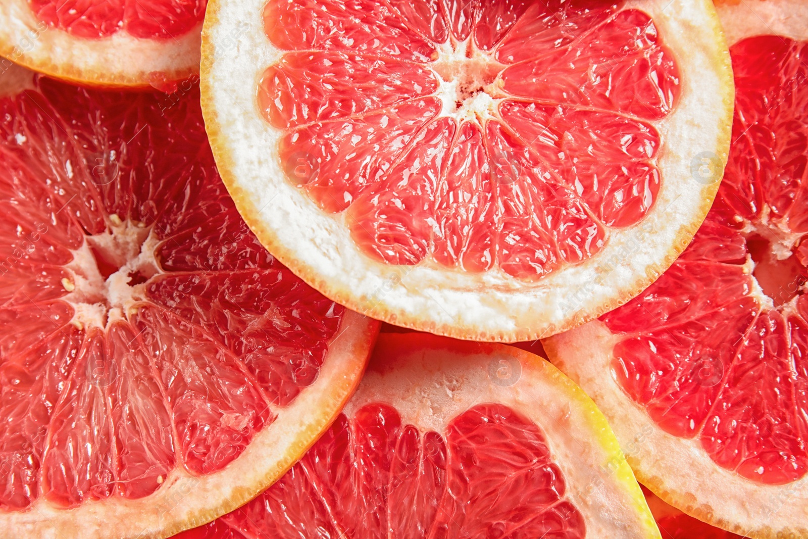 Photo of Many sliced fresh grapefruits as background, top view