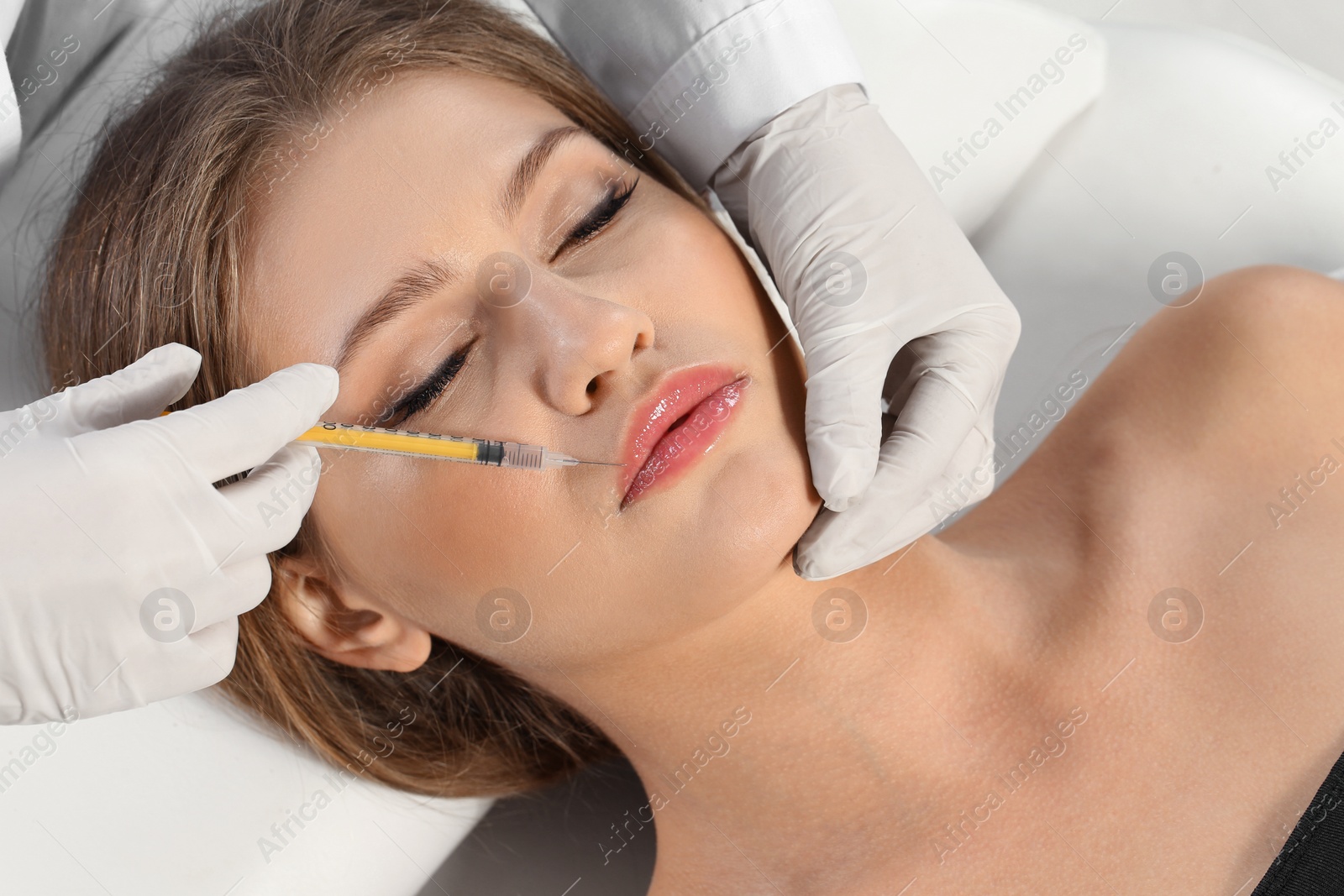 Photo of Young woman getting lips injection in clinic. Cosmetic surgery