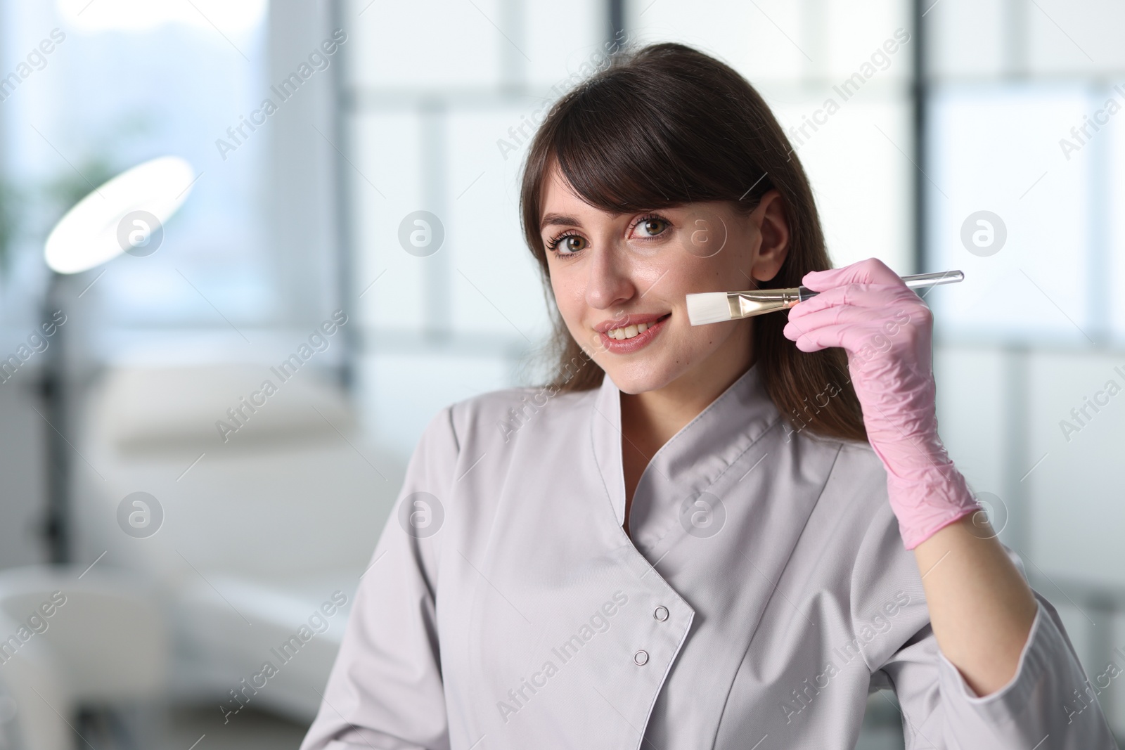 Photo of Cosmetologist with cosmetic brush in clinic, space for text