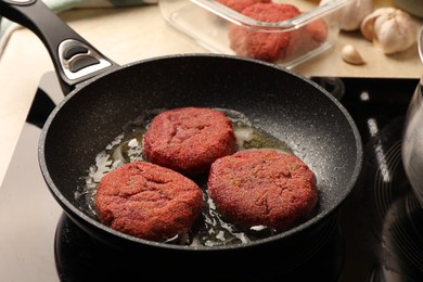 Cooking vegan cutlets in frying pan on stove, closeup