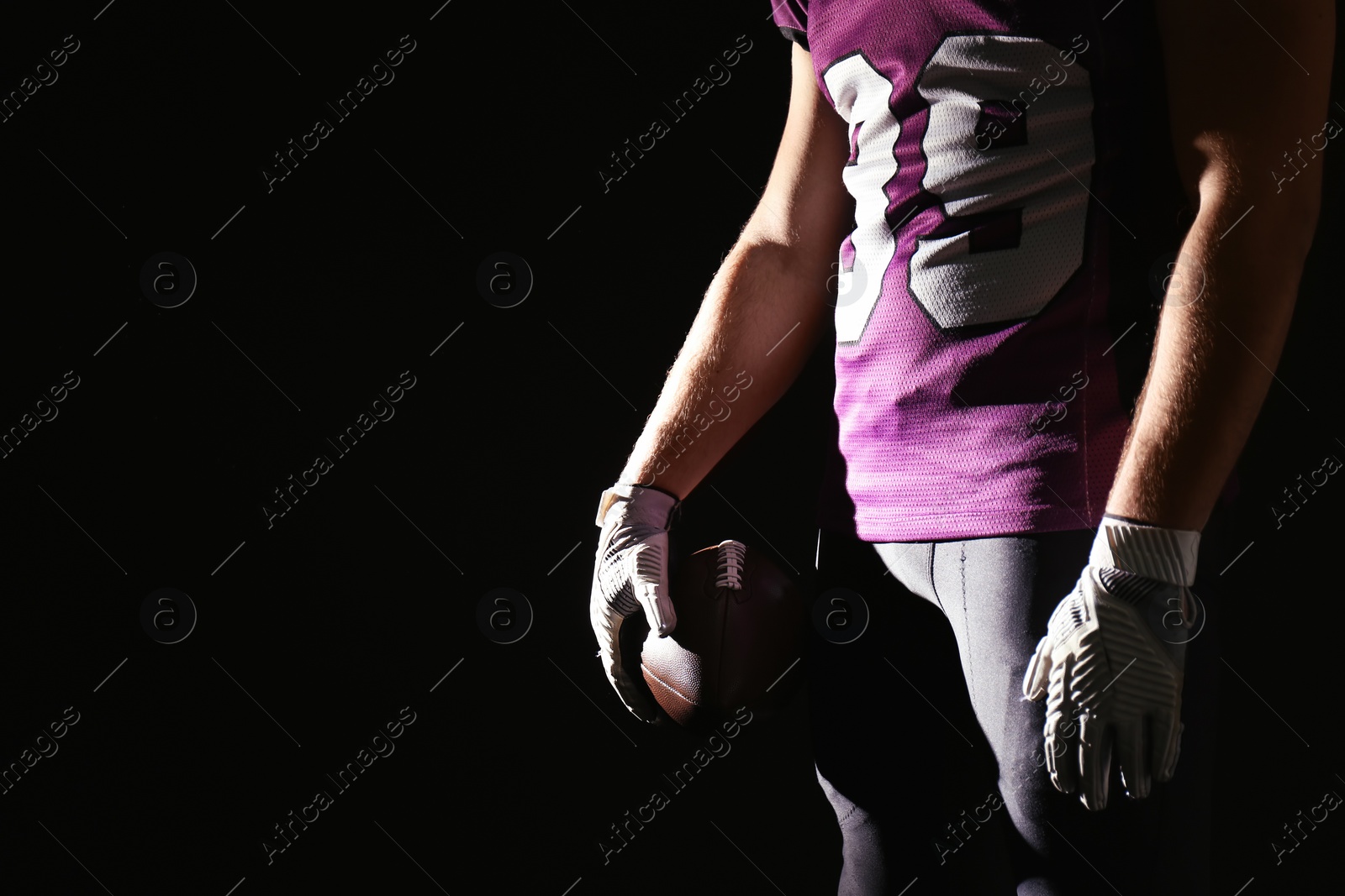 Photo of American football player with ball on dark background, closeup. Space for text