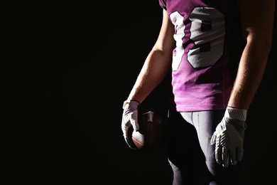 American football player with ball on dark background, closeup. Space for text