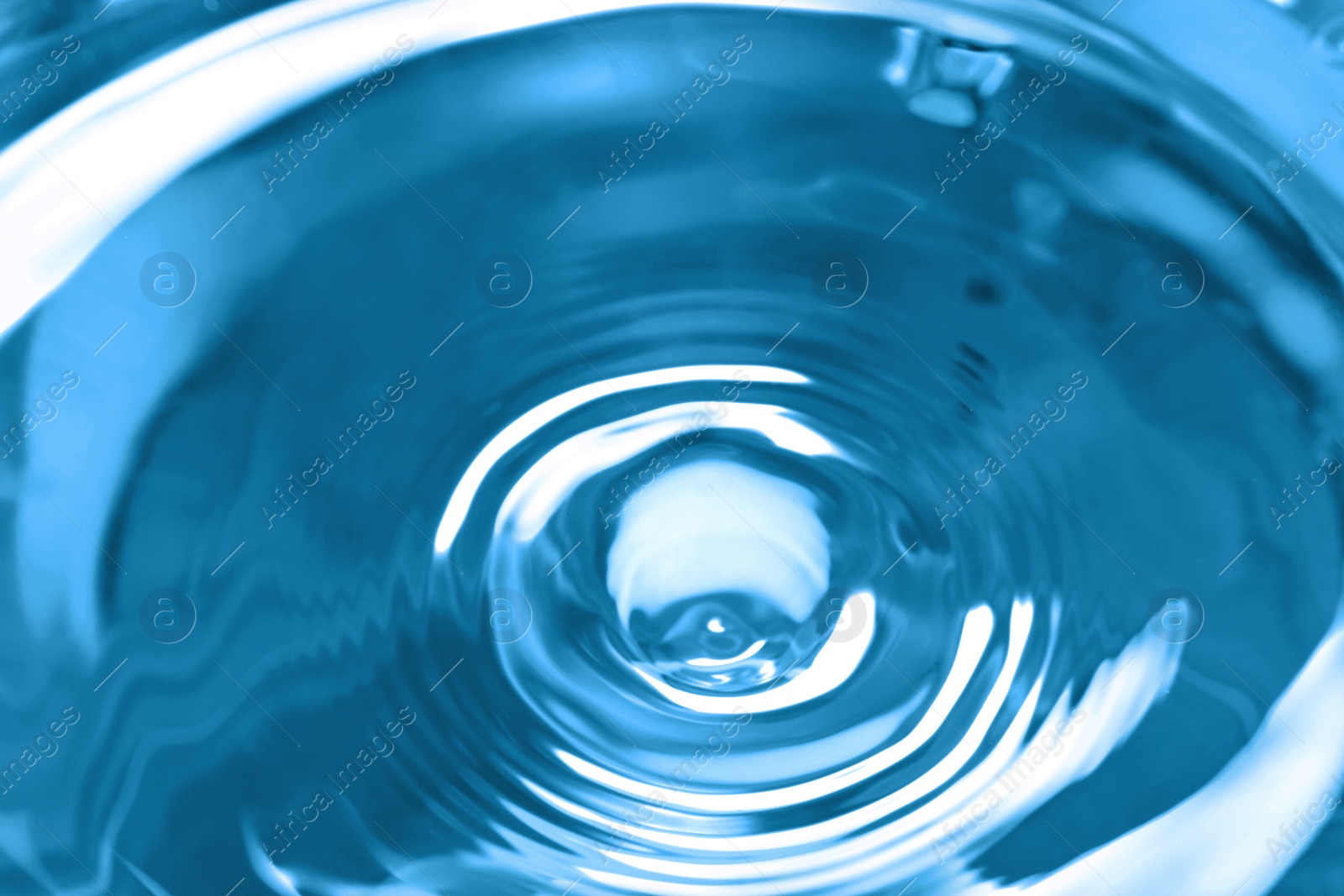 Photo of Splash of clear water on blue background, closeup