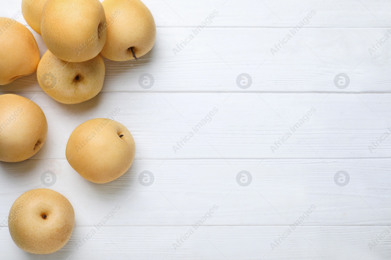 Photo of Ripe apple pears on white wooden table, flat lay. Space for text